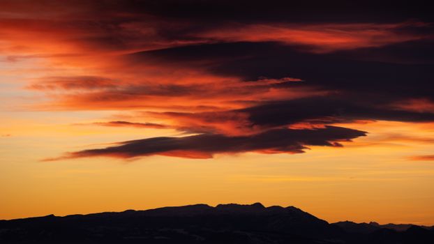 Captivating sunset with vibrant clouds over silhouetted mountains, perfect for nature-themed projects.