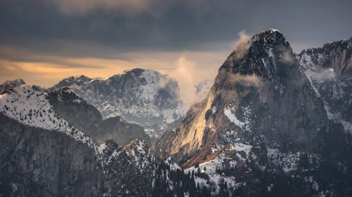 Free A stunning mountain range covered in snow under an overcast sky during sunset. Stock Photo