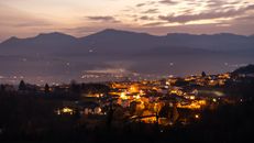 Captivating aerial view of illuminated town against a mountainous dusk backdrop.