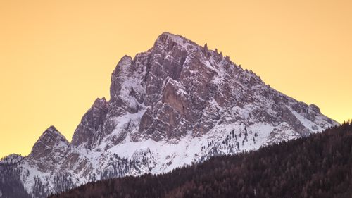 Free A breathtaking view of a snow-covered mountain peak illuminated by the warm glow of sunrise. Stock Photo