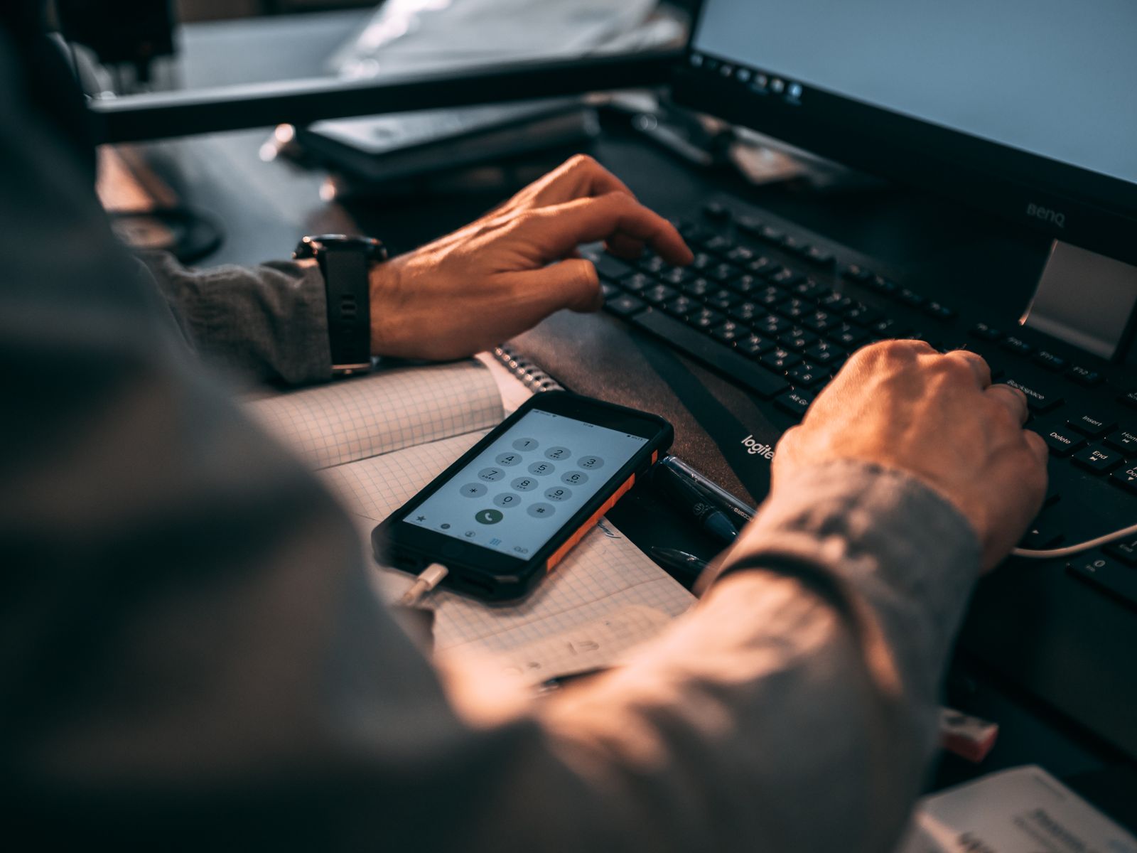 Profissional trabalhando com smartphone, planilha e computador para gestão de linhas