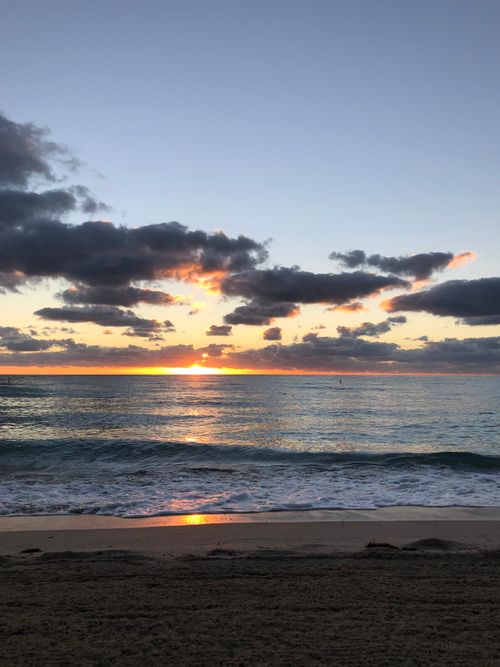 Free Breathtaking sunset over the ocean with vibrant clouds and calm waves. Stock Photo