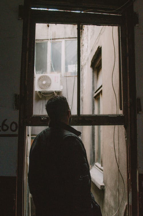 Man Standing and Looking through the Window 