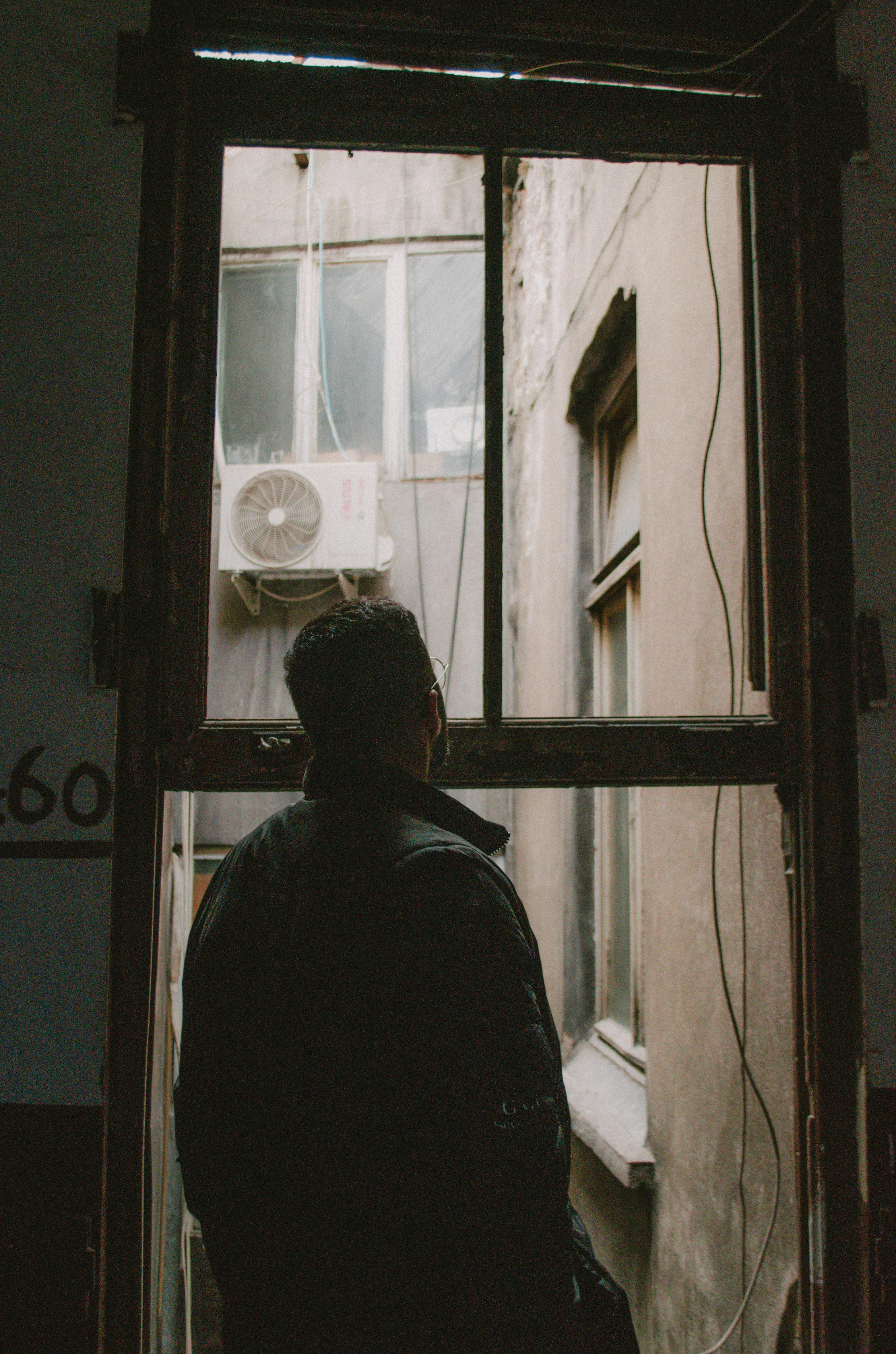 Photo of a Man Looking Outside of His Window · Free Stock Photo