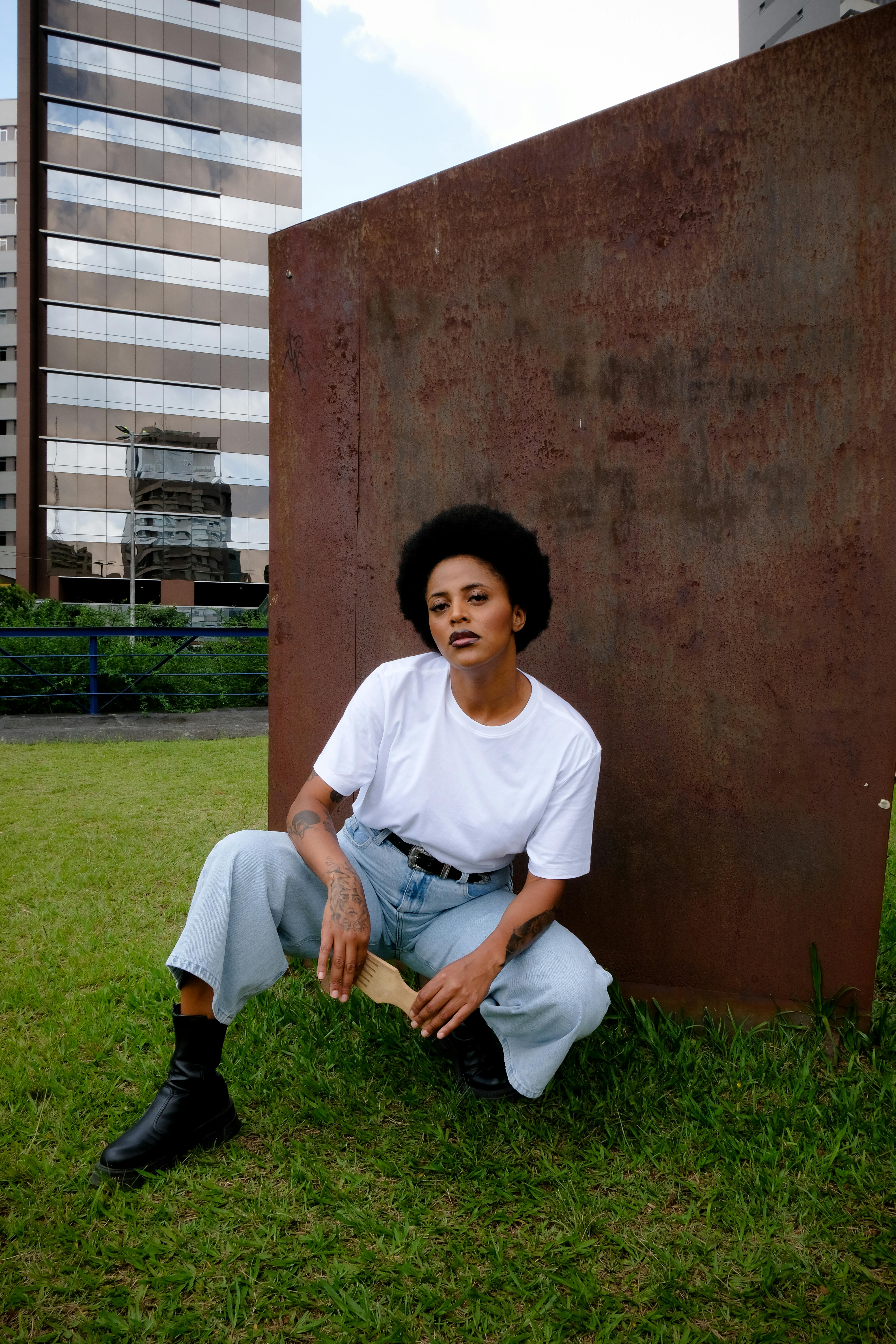Stylish woman poses casually outdoors in São Paulo cityscape.