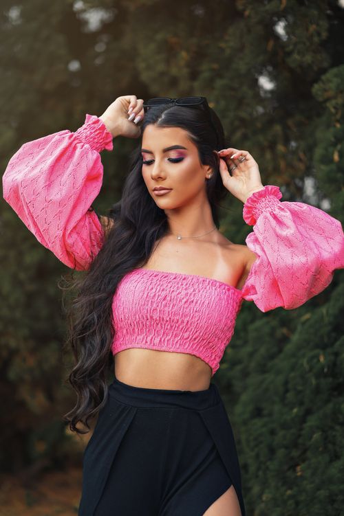 Free Stylish young woman in a vibrant pink top posing confidently outdoors. Stock Photo