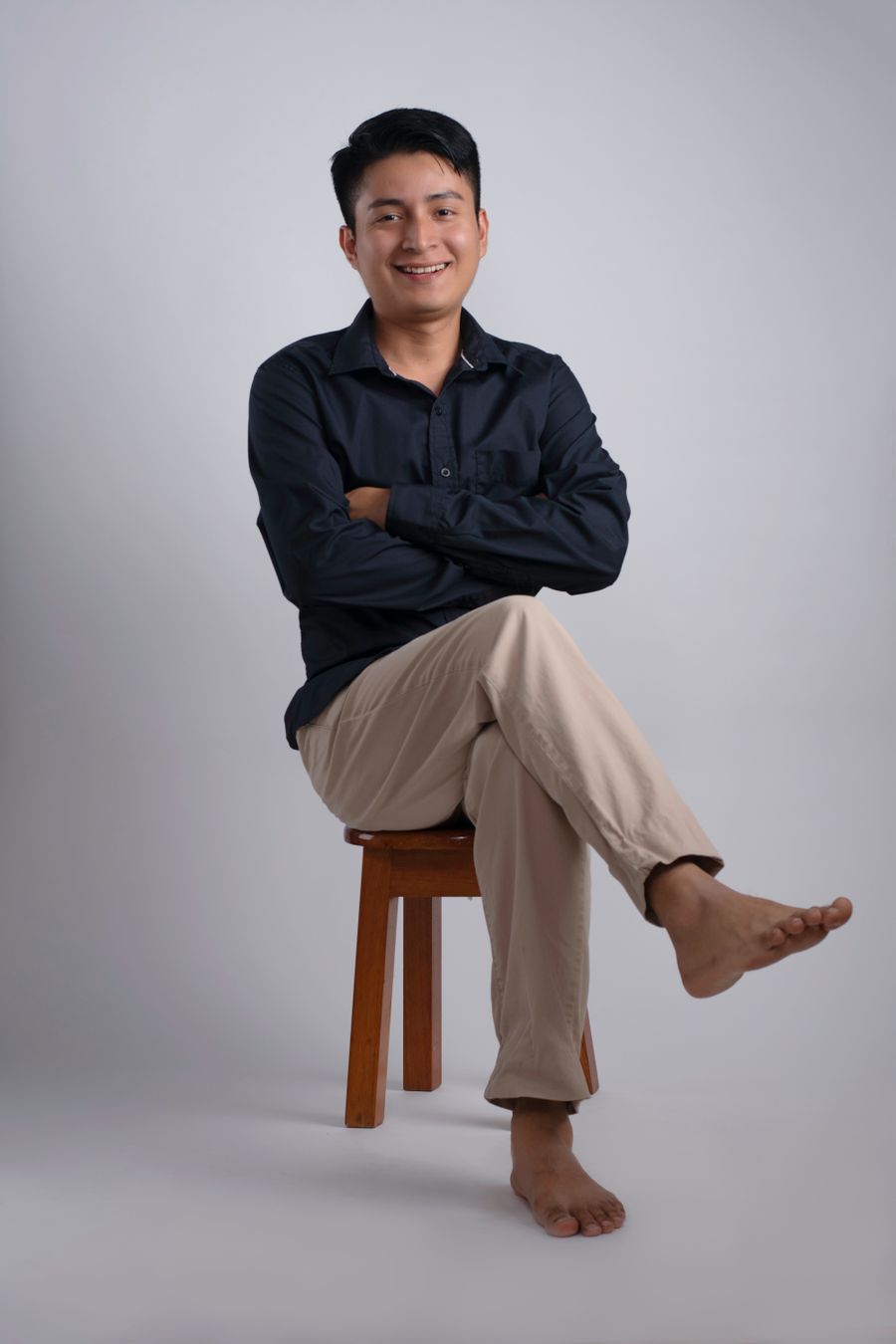 Smiling man seated on a stool in a studio — photo by Luis Armando Hernandez on Pexels