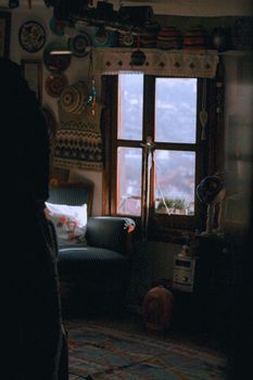 A warm and inviting room with retro decor, a window view, and comfortable seating.