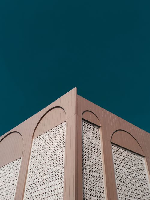 Free Low angle view of modern building facade with intricate patterns under clear blue sky. Stock Photo