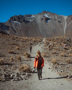 Adventurers explore a rocky mountain trail under clear blue skies. Ideal for travel and nature themes.