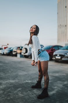 Young woman in stylish urban fashion posing confidently in a parking lot.