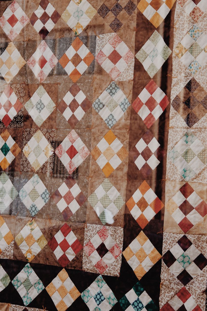 Diamond-patchwork quilt in rust, cream and slate. Photo by Ann Perkas on Pexels