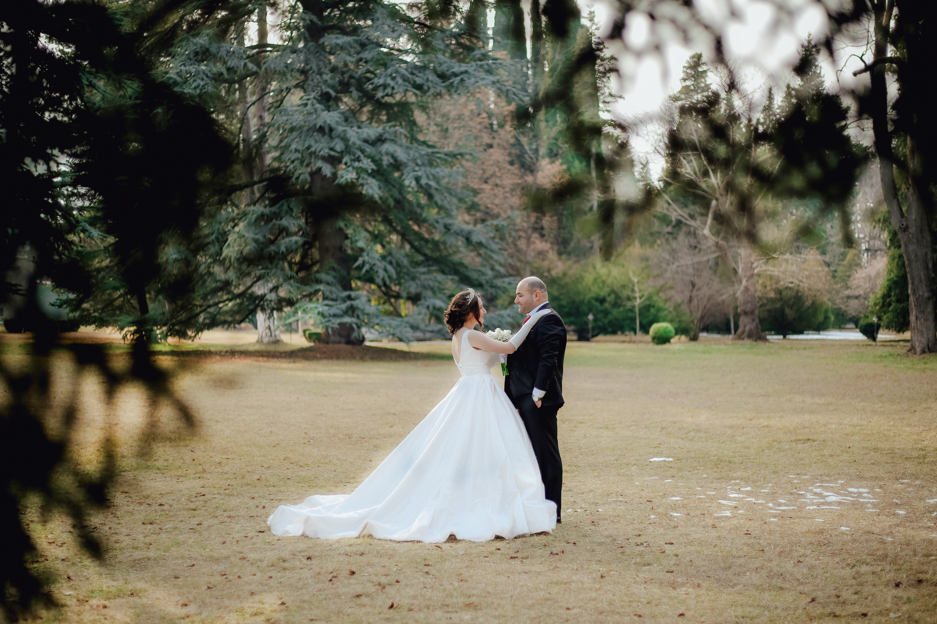 A bride and groom share a tender moment outdoors, surrounded by natural beauty.