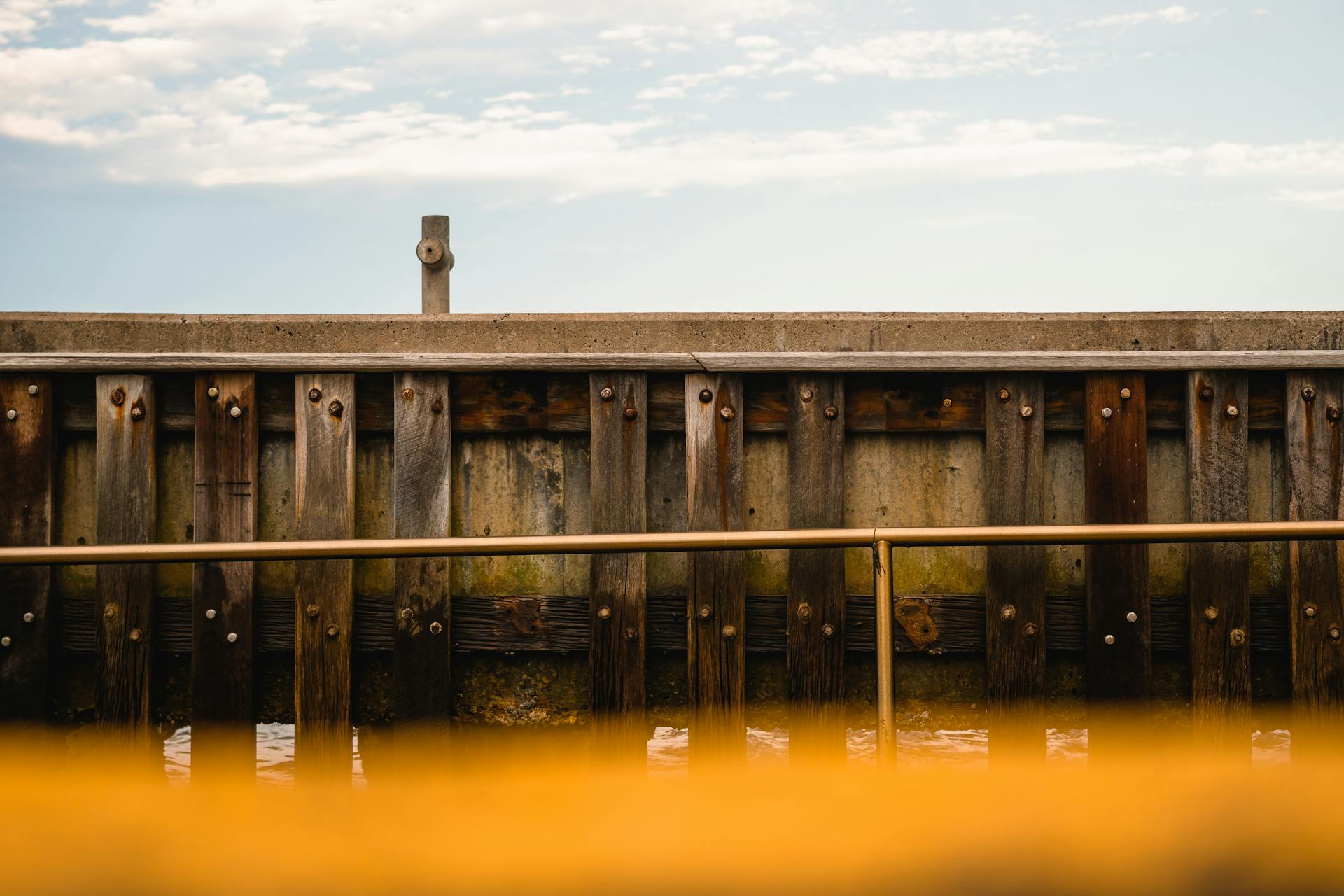 Wooden dock with aged metal railings against a clear sky, offering a rustic outdoor scene.