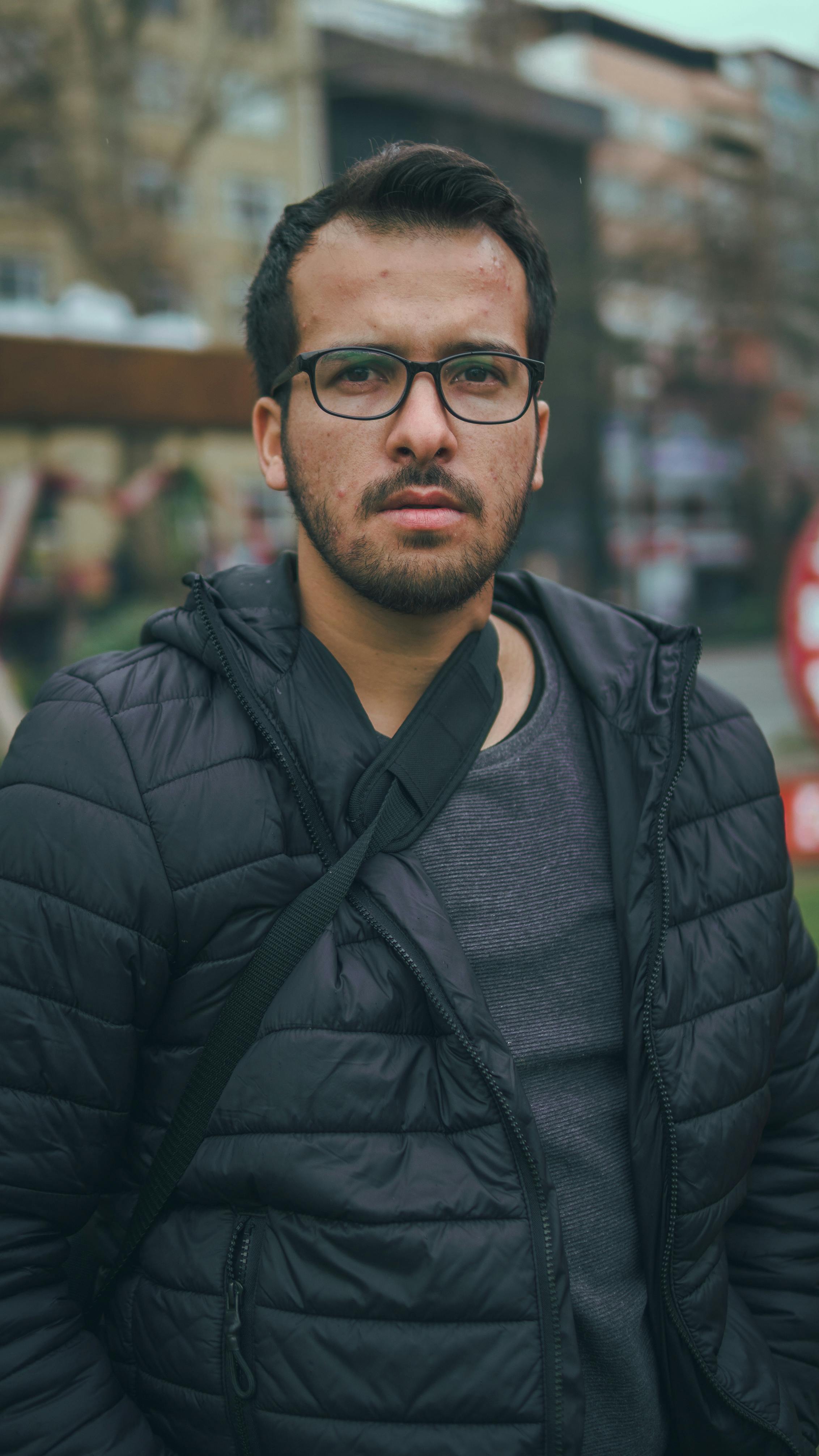 Portrait of a bearded man wearing a jacket and glasses outdoors in İstanbul.