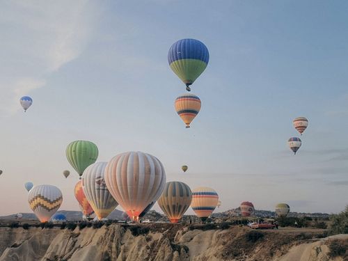 Free Colorful hot air balloons float above Cappadocia's unique rock formations at sunrise. Stock Photo