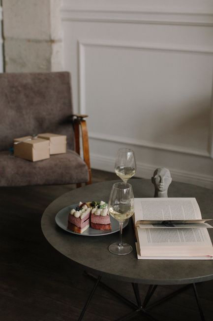 Relaxing living room setting with cake, wine, and an open book on a coffee table.