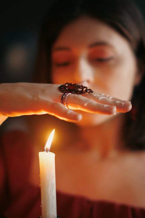 Woman Holding Hand over Candle