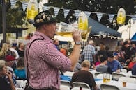 在热闹的啤酒节庆祝活动中，一名男子在户外享用着一大杯啤酒
