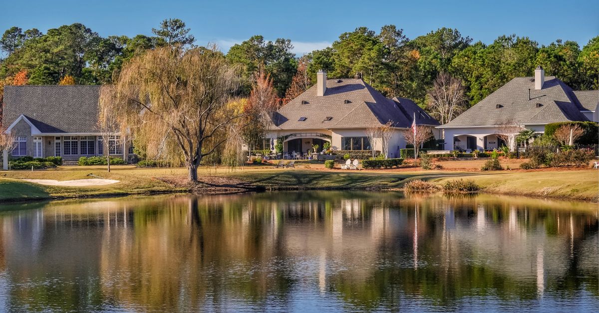 Picturesque lakeside view of charming houses surrounded by fall foliage in Wilmington, NC.