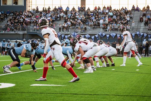 Free Players in action during a competitive high school football game at an outdoor stadium. Stock Photo