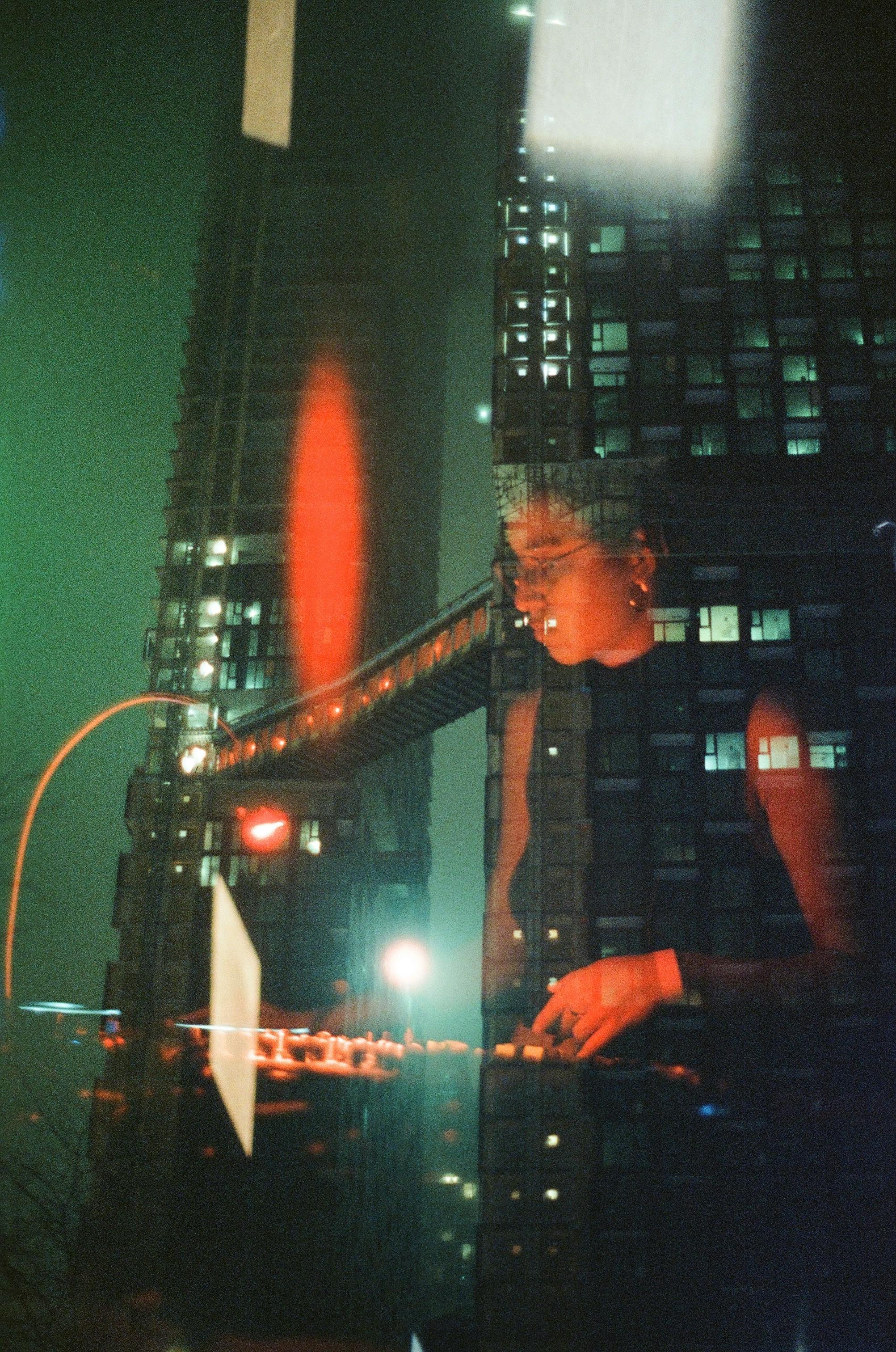 A creative blend of a woman working and towering skyscrapers at night.