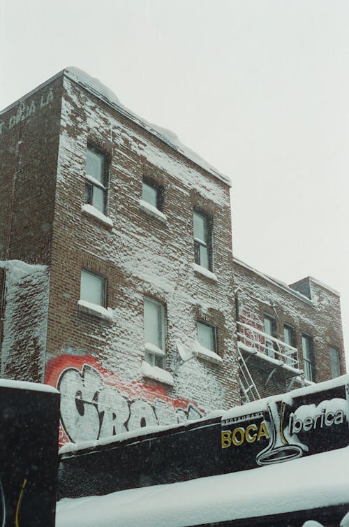 Snow on Brick Building in Town