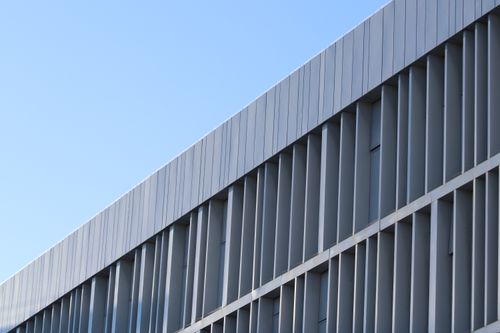 Free Close-up of a modern building facade with geometric patterns and clear blue sky. Stock Photo