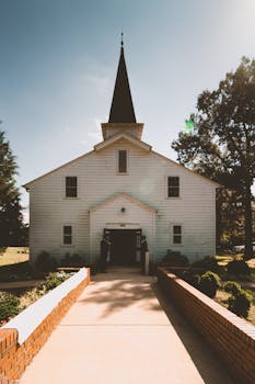 一座拥有尖塔和木制建筑的风景如画教堂，坐落于晴朗的乡村