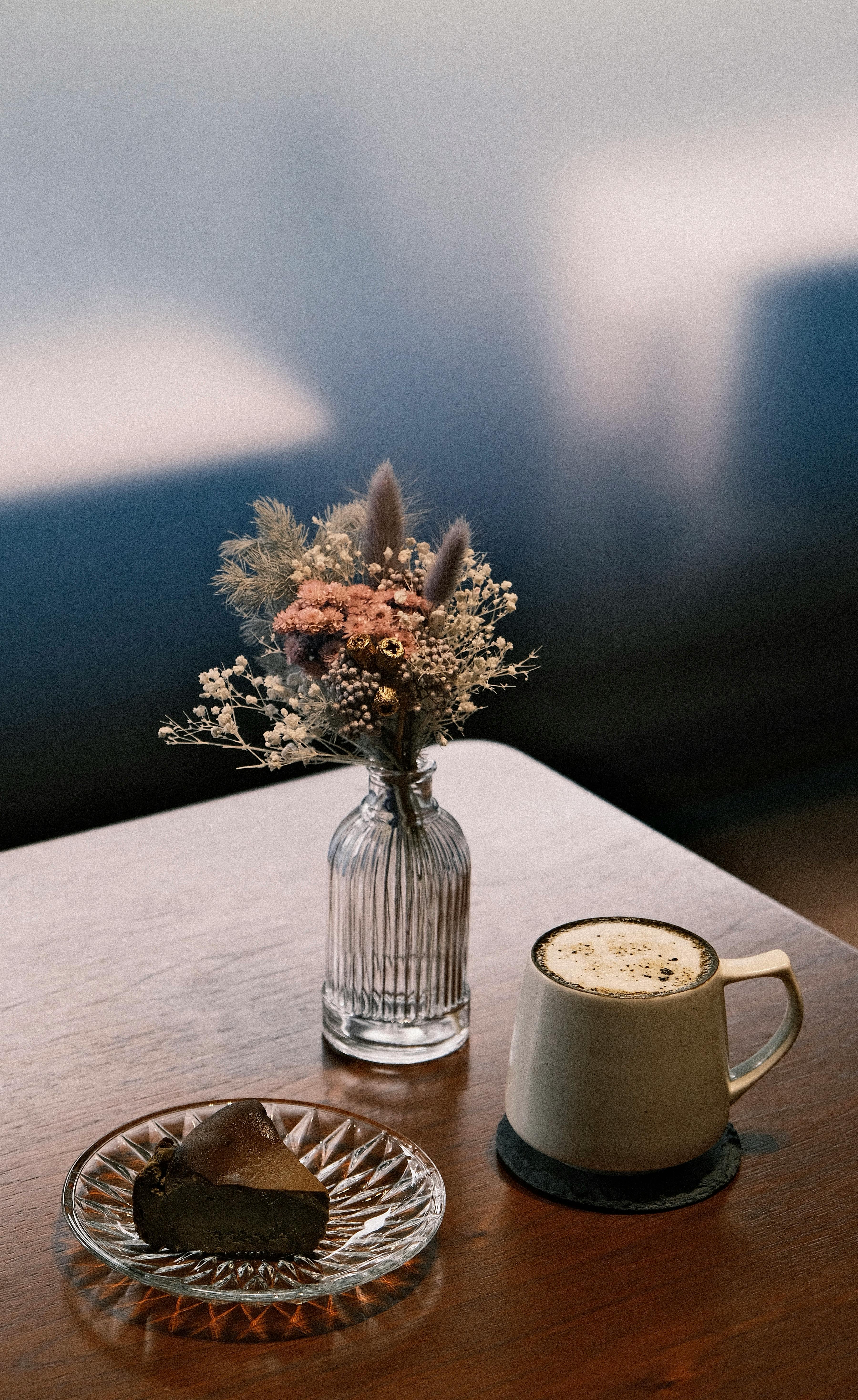 Warm coffee and chocolate cake with dried flowers on a wooden table.