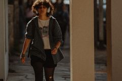 Young woman in casual streetwear walking on a city sidewalk wearing headphones.