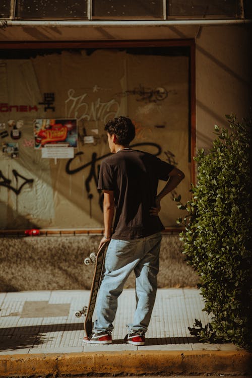 Skater in Jeans Standing on Sidewalk