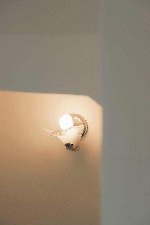 Wall sconce glowing on a plaster wall, H&CO on Pexels