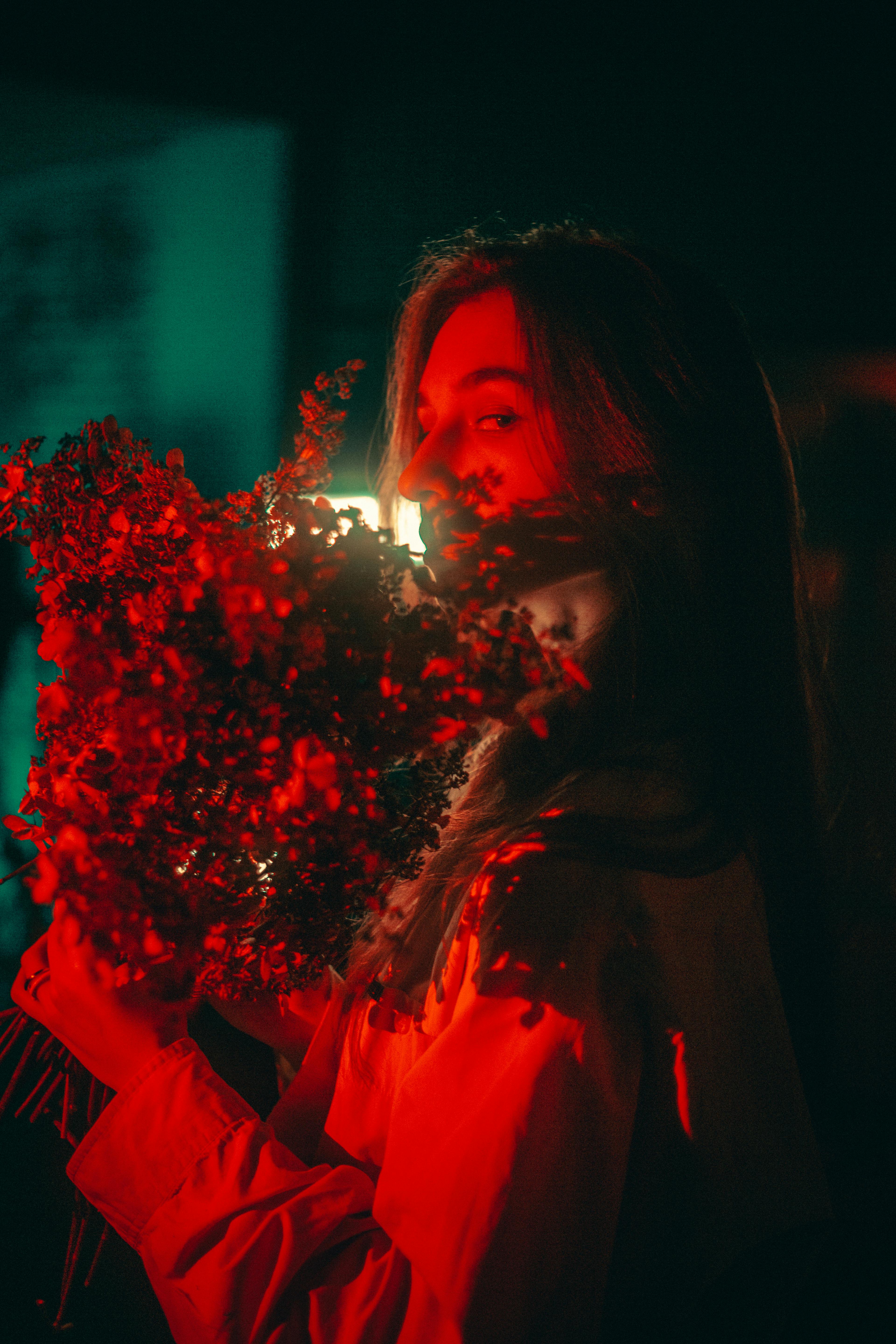 Artistic portrait of a woman with a bouquet, highlighted by intense red lighting, in Kyiv.