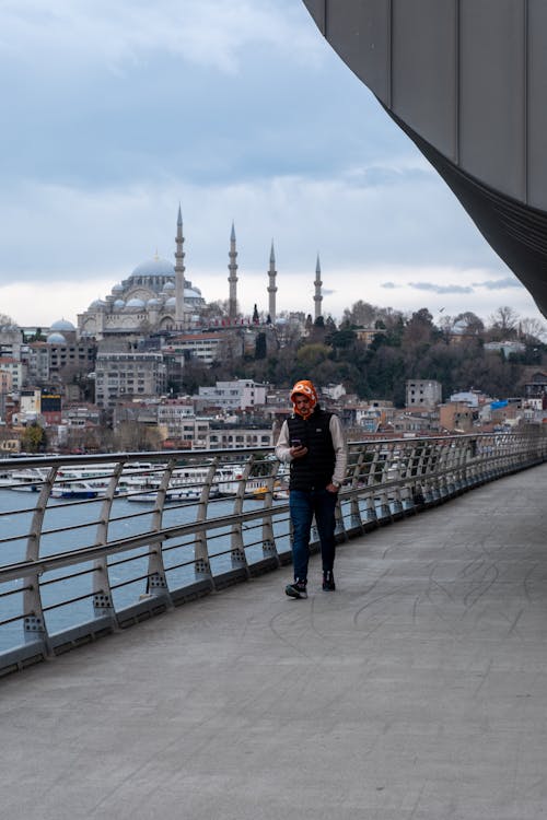 Man Walking on a Bridge and Mosque in Background