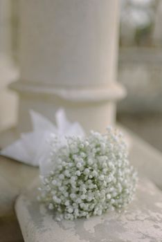 Delicate baby's breath bouquet resting on a stone surface with a soft focus background.