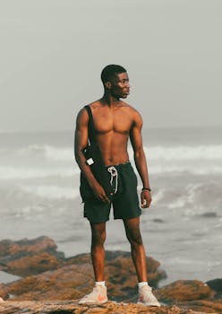 A man stands confidently on a rocky beach in Ghana, exuding strength and relaxation.