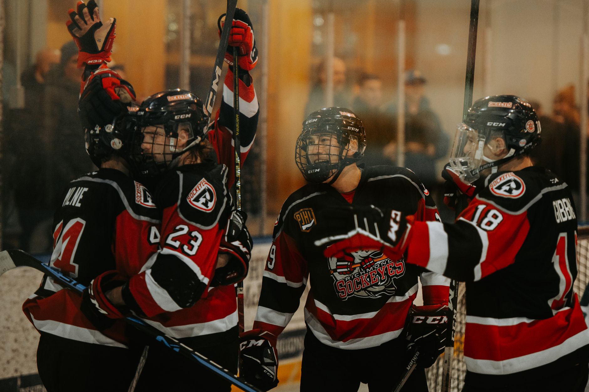 Ice hockey players in red jerseys celebrating a victory during an indoor match.