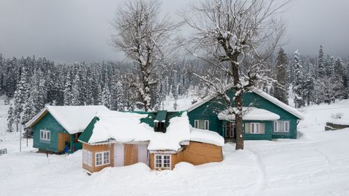 Free Beautiful snow-covered cabins surrounded by a frosty forest in Gulmarg during winter. Stock Photo