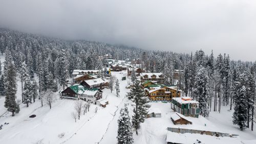 Free Picturesque winter view of Gulmarg, showcasing snow-covered houses and pine trees. Stock Photo