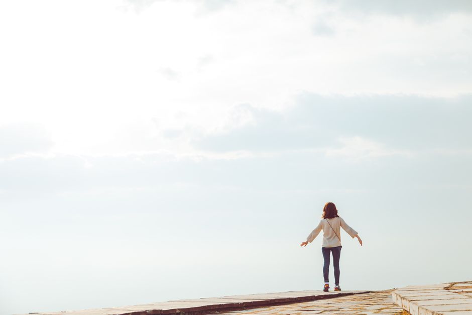 A woman standing on a hilltop embracing the open sky with a sense of freedom