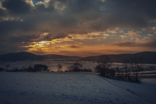 Breathtaking winter sunset over snowy fields and hills in Styria, Austria.