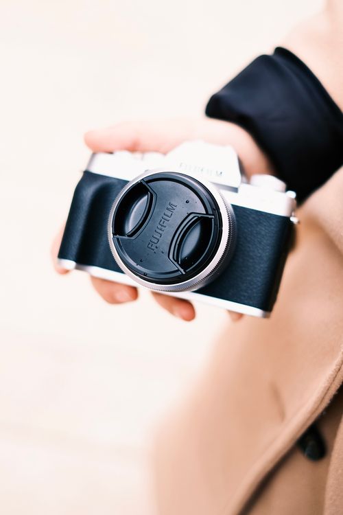 Free Close-up of a person holding a black and silver camera with lens cap. Stock Photo
