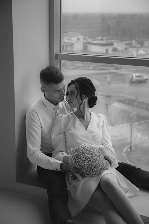 Couple Sitting Face to Face on a Window Parapet