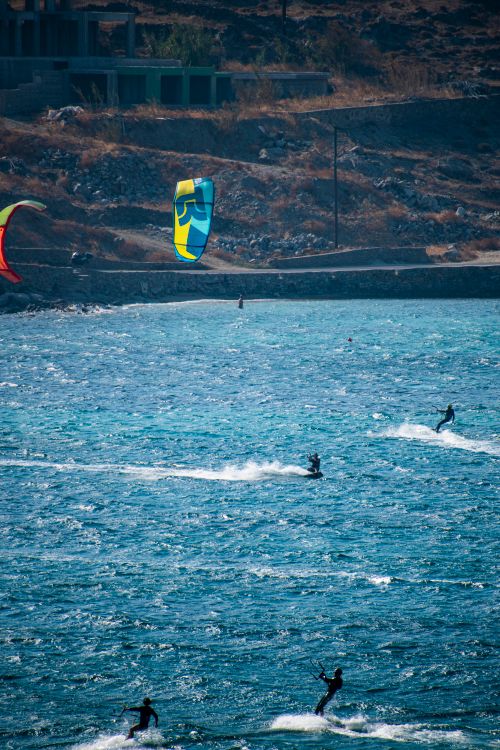 Free Kitesurfers glide over blue ocean waves on a sunny day, capturing thrilling adventure. Stock Photo