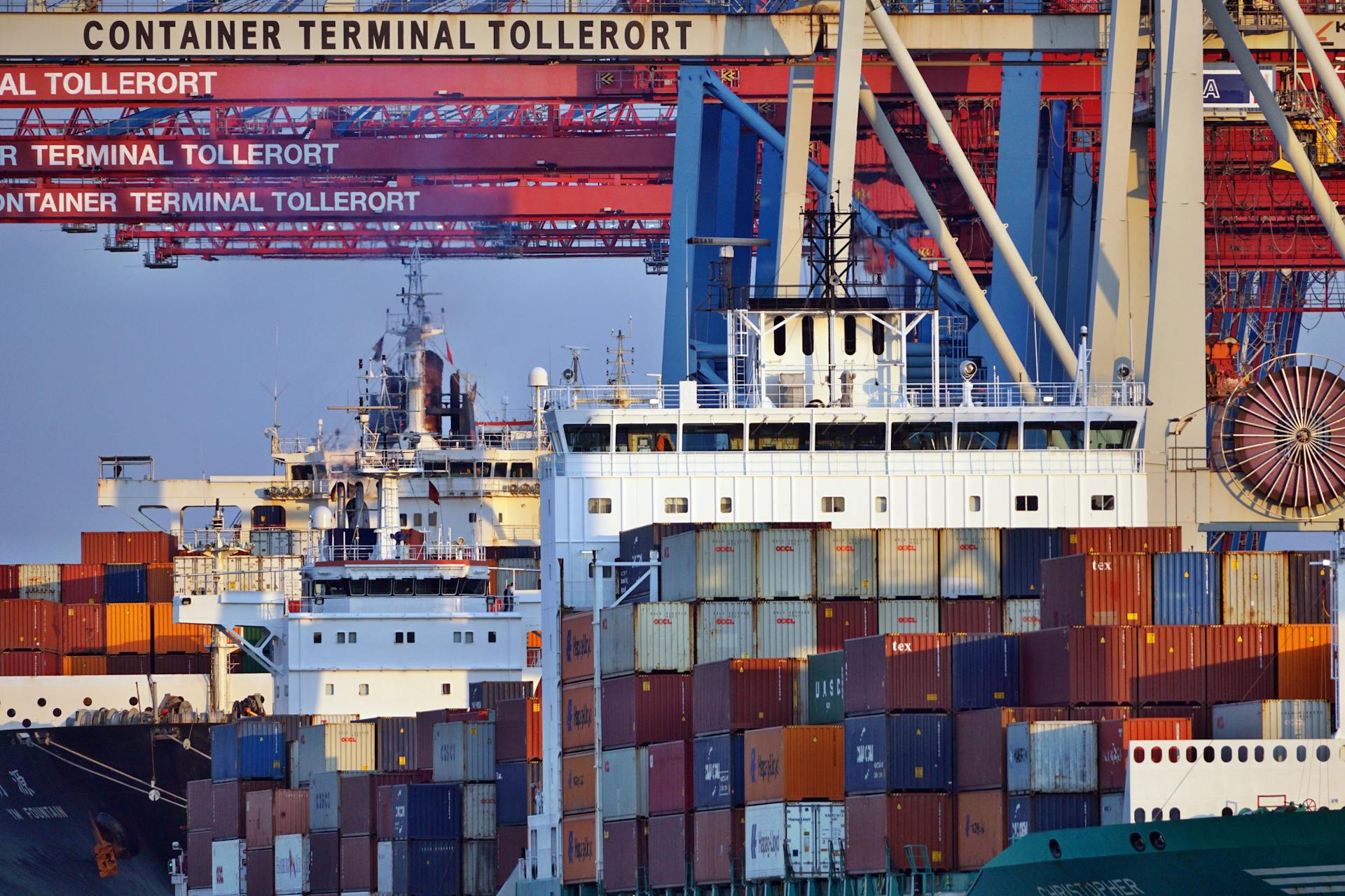 Container ships docked at Tollerort Terminal, Hamburg during sunset.