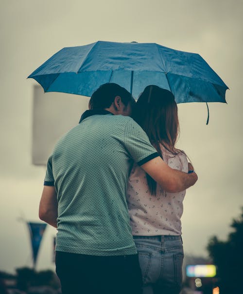 Uomo Che Abbraccia La Donna Mentre Si Tiene L'ombrello