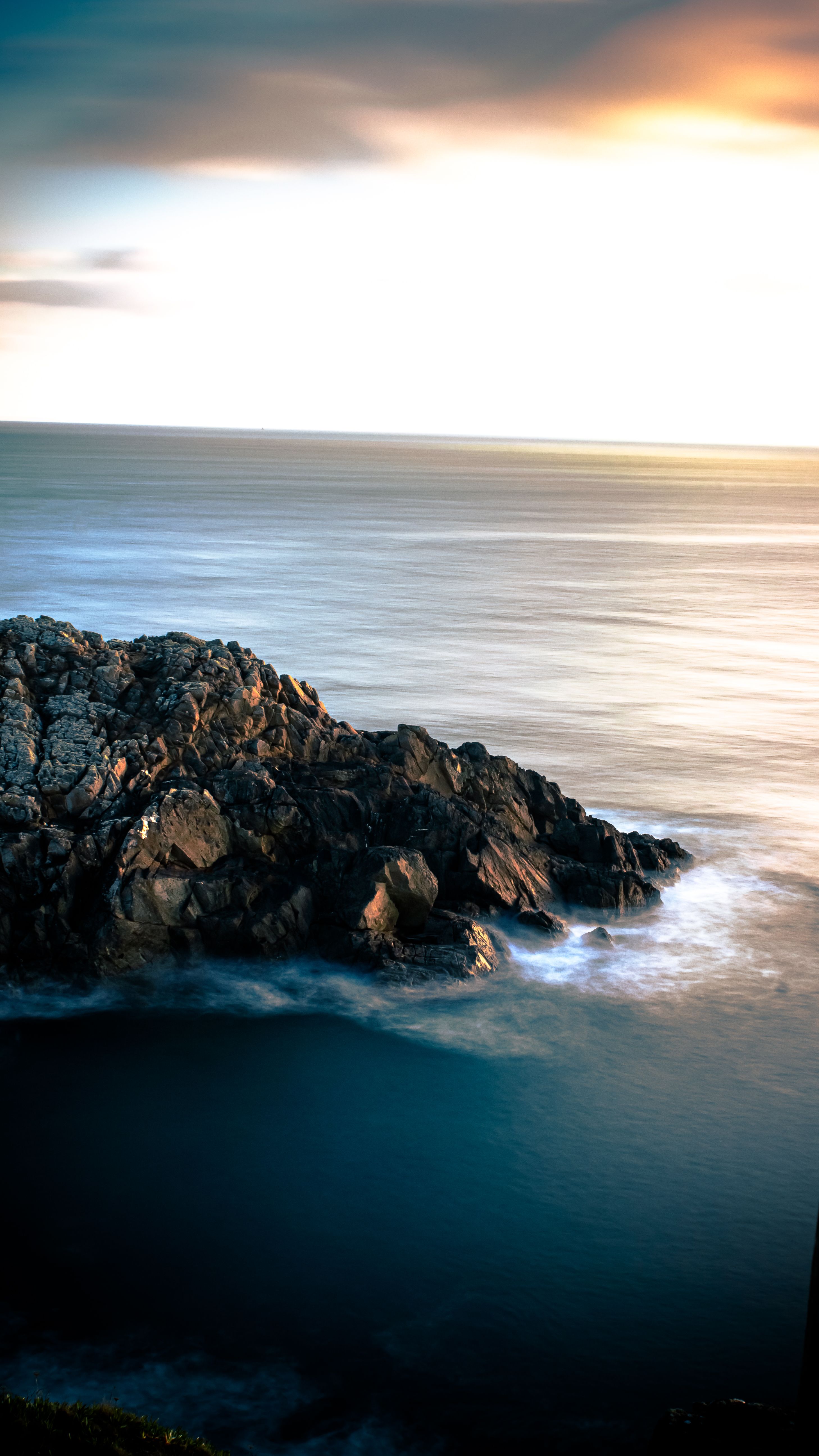 A serene sunset over a rocky ocean shoreline, capturing the tranquil beauty of nature.