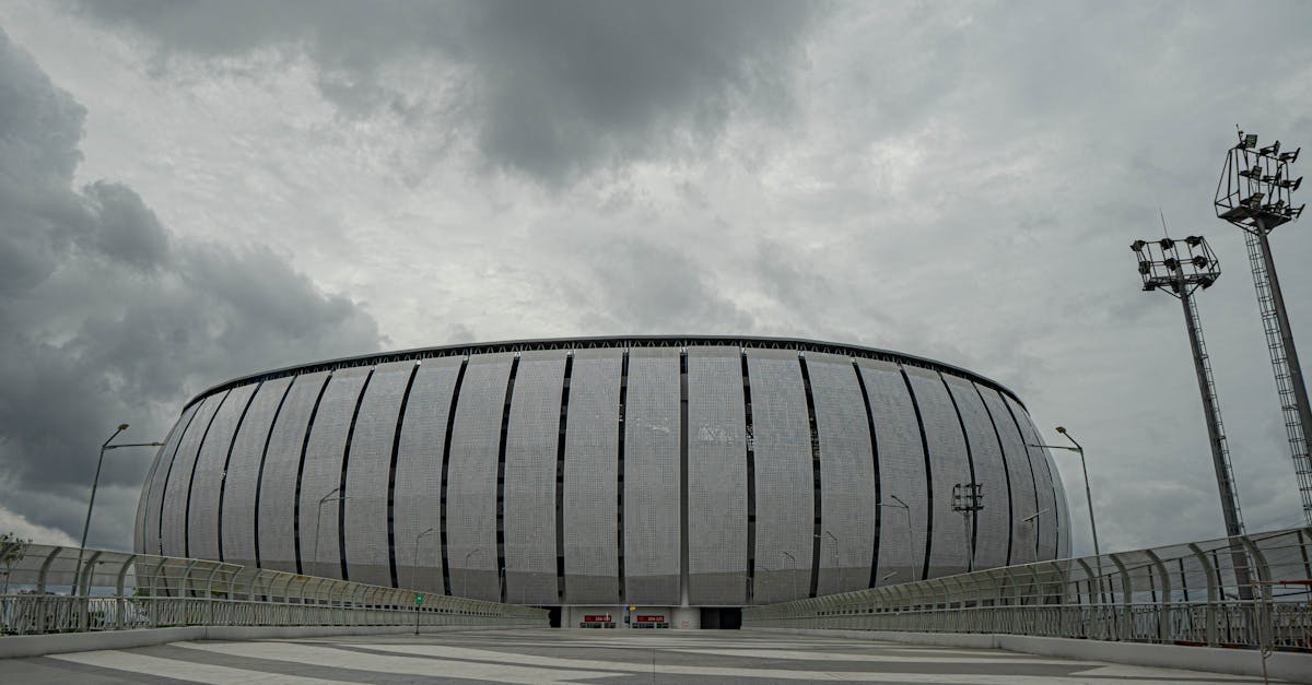 Panoramic view of Jakarta International Stadium with dramatic cloudy skies above, showcasing modern architecture.