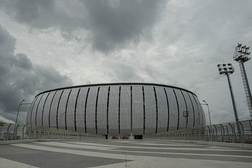 Free Panoramic view of Jakarta International Stadium with dramatic cloudy skies above, showcasing modern architecture. Stock Photo